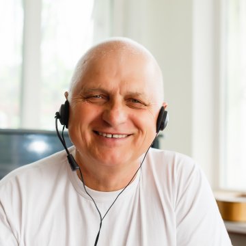 A man with a VOIP headset on, smiling a lot